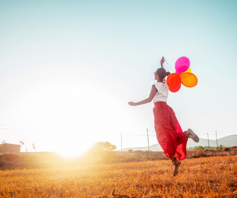 Frau mit bunten Luftballons auf einem Feld