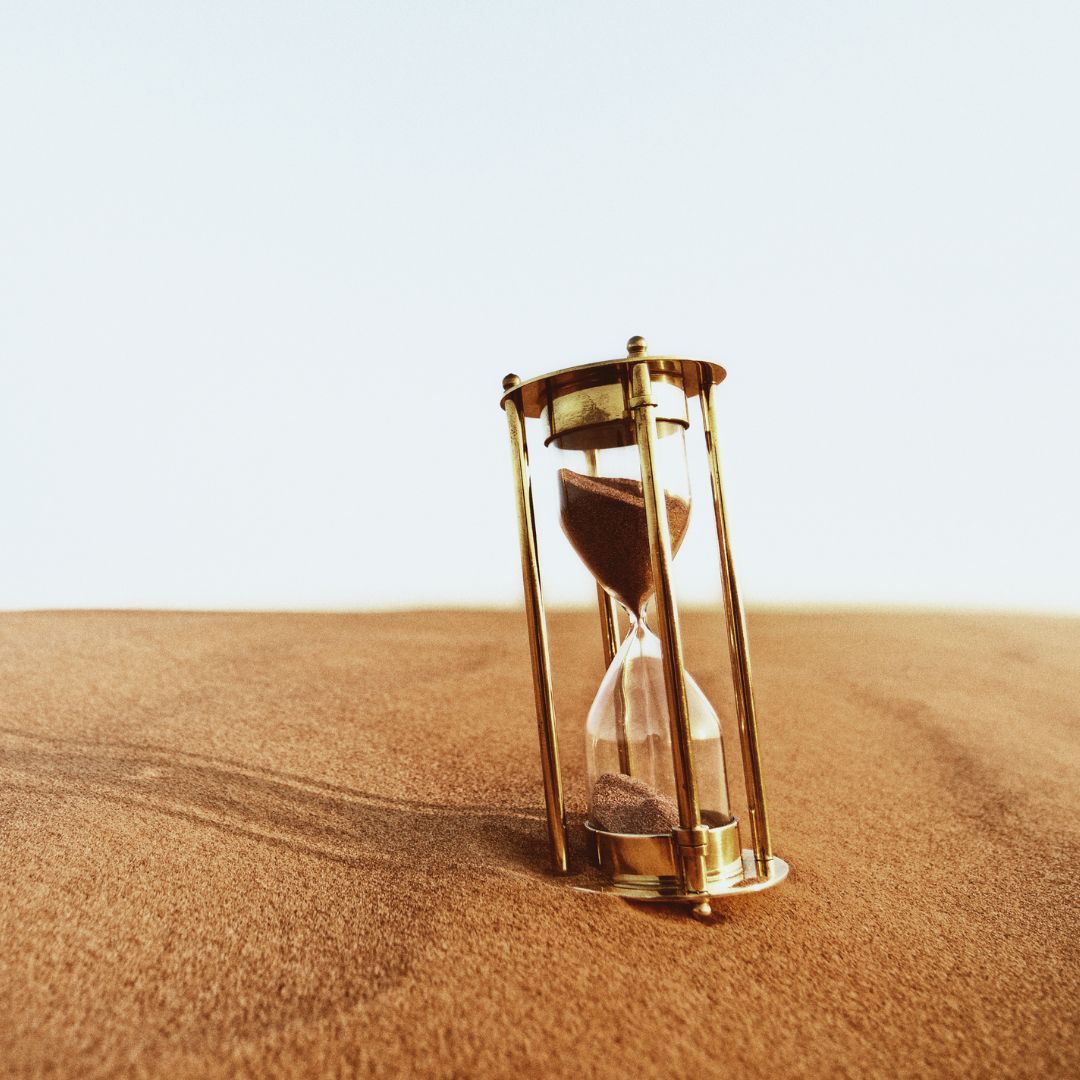 Eine große alte Sanduhr steht in der Wüste.