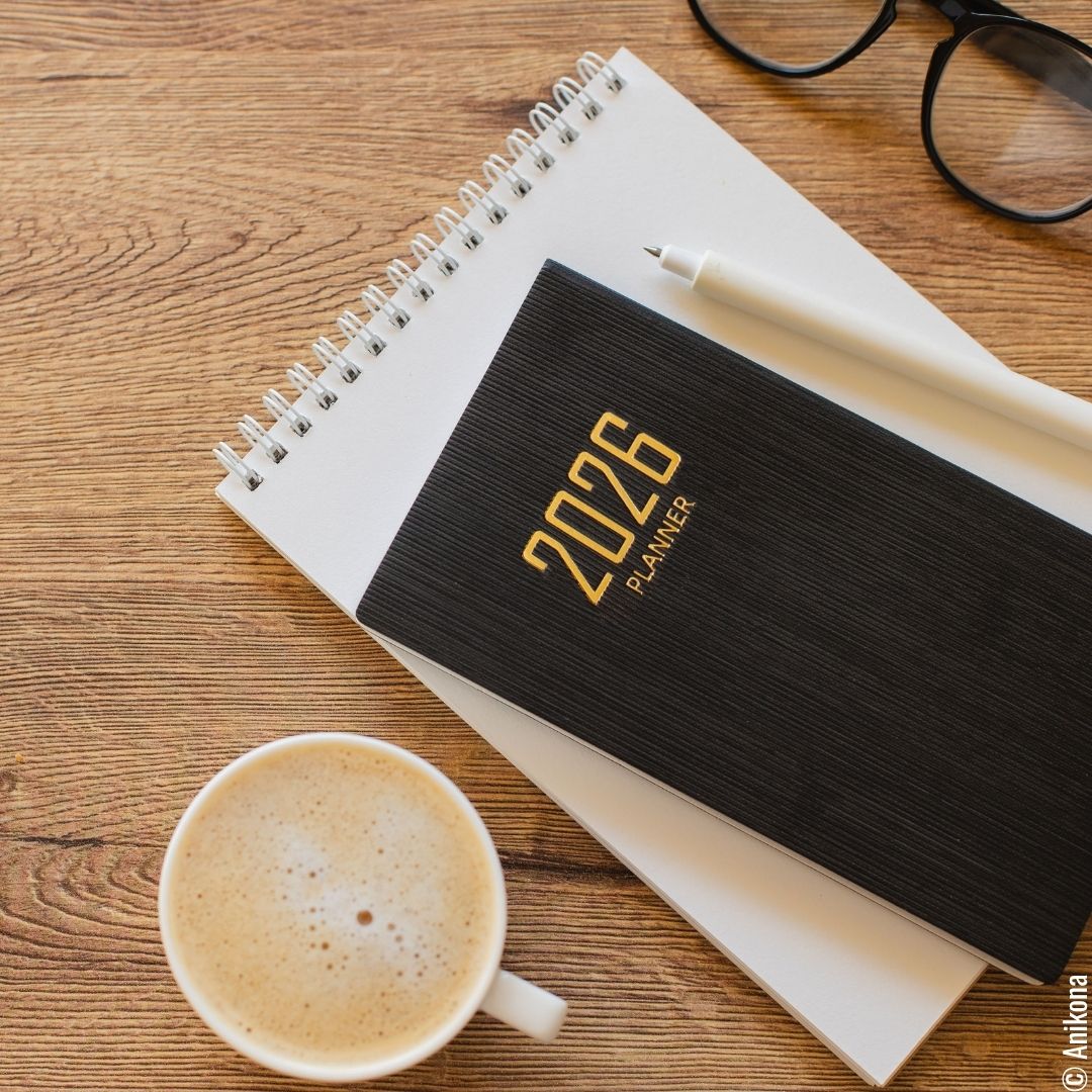 Schreibtisch mit Terminplaner, Notizblock und Stift